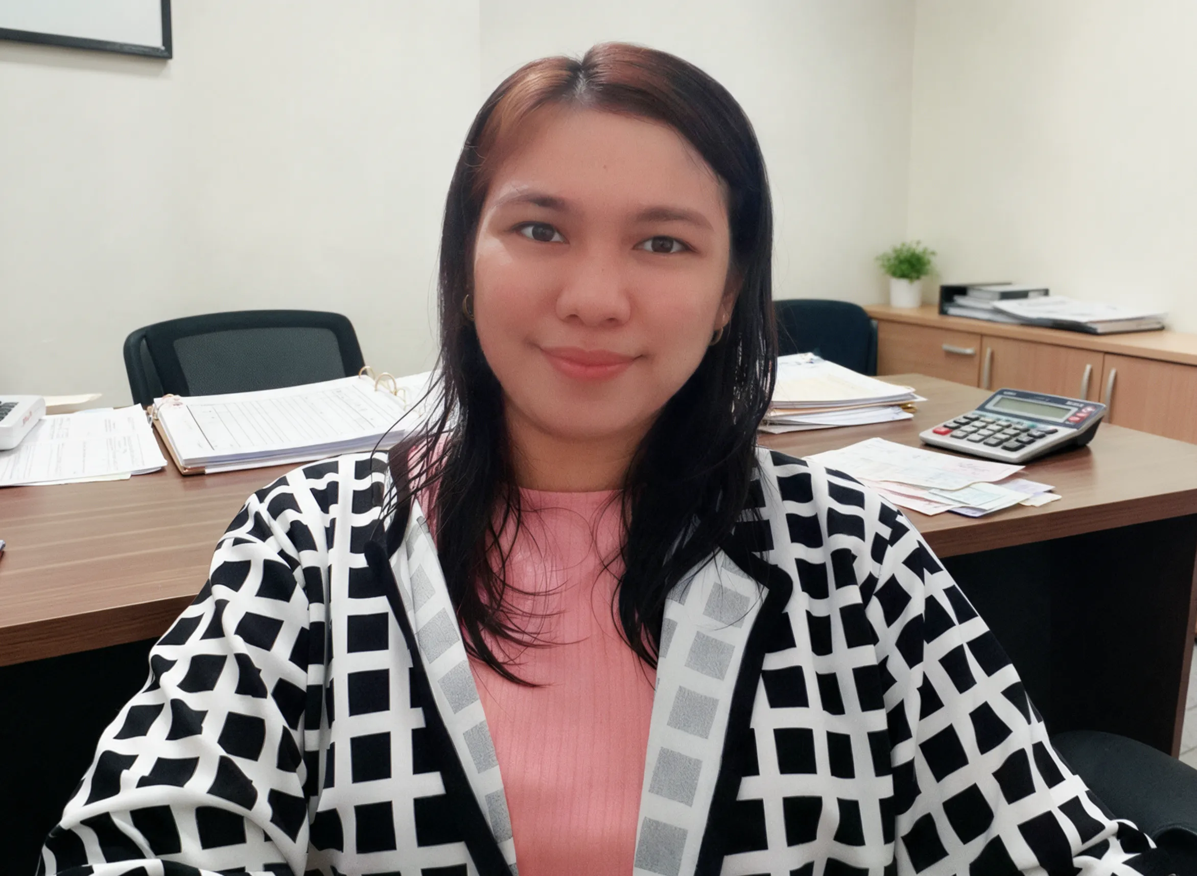 Woman smiling in checkered blazer at office desk